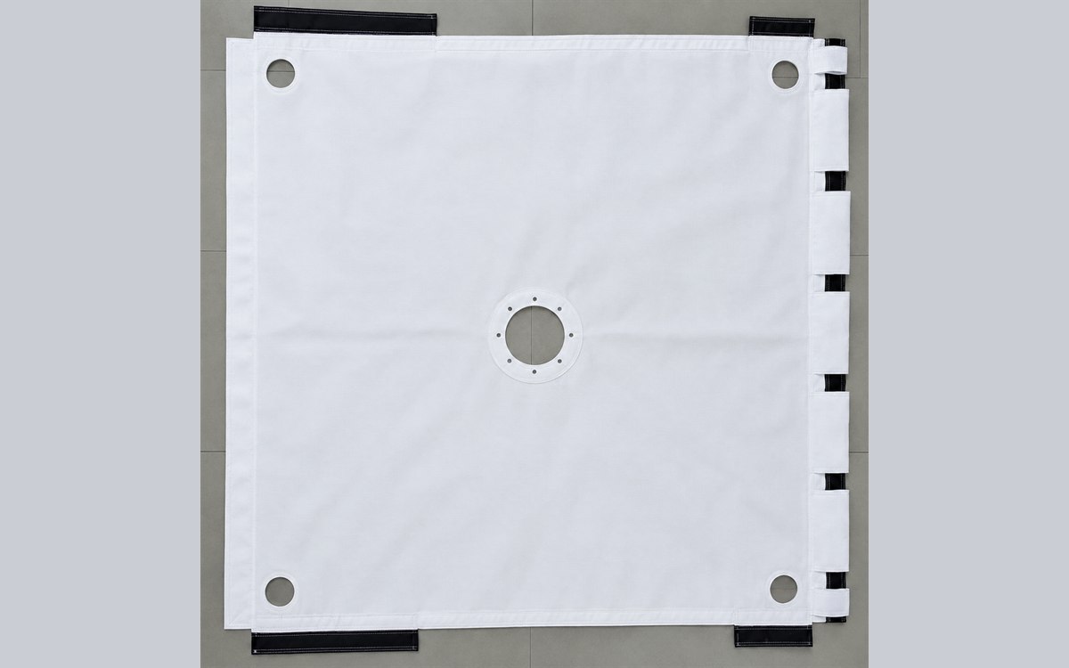 A finished DFR filter press cloth laid flat, centre feed neck, corner eyelets and fastening tabs