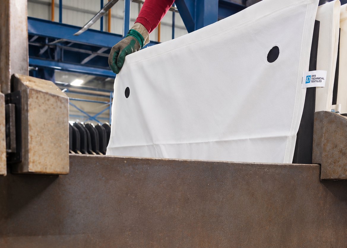 A DFR filter press cloth being dressed onto a plate at a customer's plant, the DFR label visible at the cloth edge