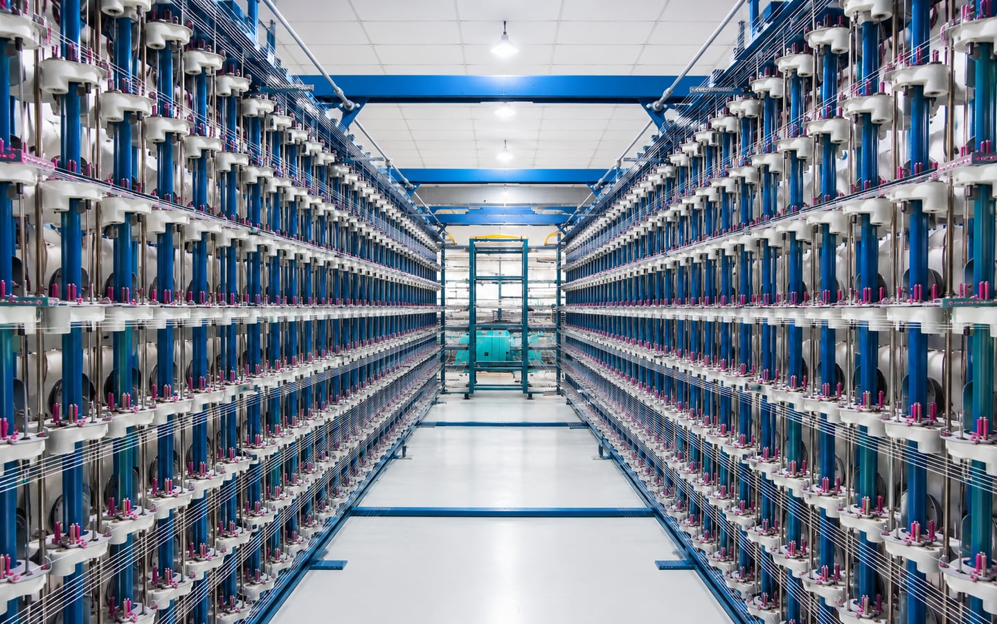 Creel hall at the DFR plant, yarn packages racked either side of a central aisle feeding the warping section
